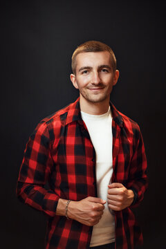 Confident Smile. Handsome Guy In A Red Checkered Shirt On A Black Background. Clothing Style.