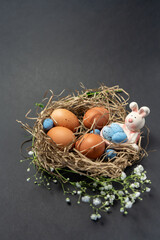 Natural eggs with Easter eggs, feathers in a nest on a dark background. Top view, Happy Easter. Easter Holiday,