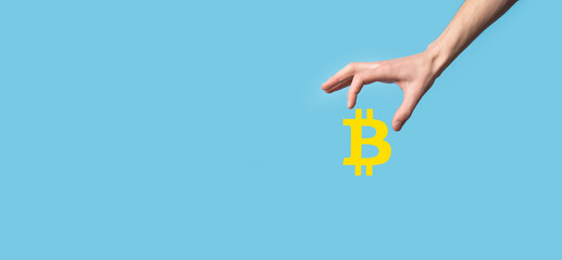 Male hand holding a bitcoin icon on blue background. Bitcoin Cryptocurrency Digital Bit Coin BTC Currency Technology Business Internet Concept.