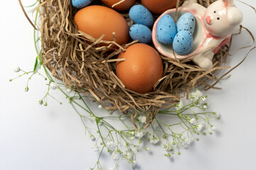 Fototapeta premium Natural eggs with Easter eggs, feathers in a nest on a dark background. Top view, Happy Easter. Easter Holiday,