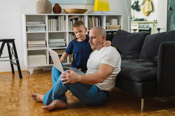 father and son using computer at home