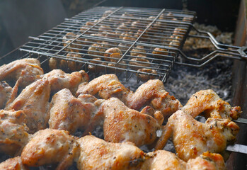 Chicken wings and mushrooms are fried on an open fire. Summer. Barbecue