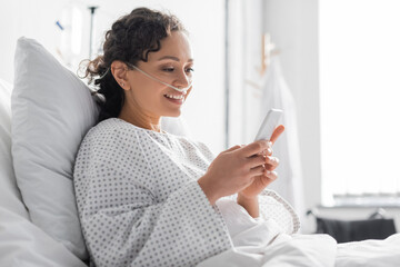 smiling african american woman messaging on mobile phone in hospital