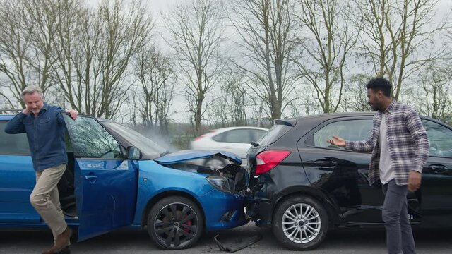 Young Couple Getting Out Of Damaged Car In Accident With Senior Driver
