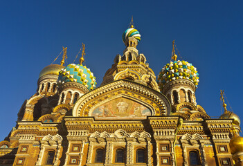 Fototapeta na wymiar St. Petersburg. Domes of Church of Savior on Spilled Blood against the background of blue sky. Icon on the facade and details of the richly decorated Cathedral of the Resurrection of Christ, exterior
