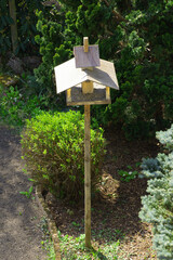 bird feeder in the form of a big house standing still in the ornamental garden after winter