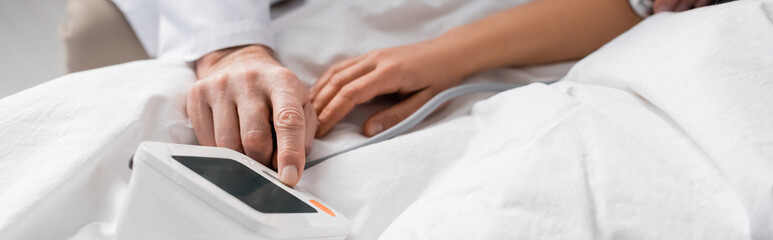 partial view of doctor measuring blood pressure and heartbeat rate of patient, banner