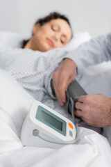 doctor measuring blood pressure of sick african american woman on blurred background