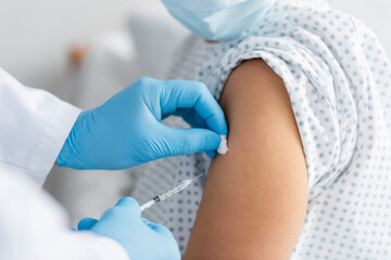 Fototapeta premium partial view of doctor in latex gloves doing injection of vaccine to woman in medical mask