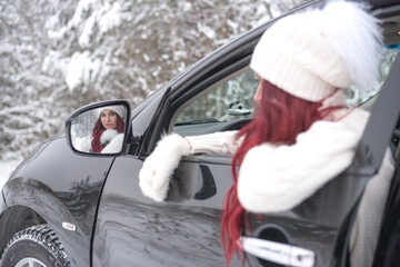 beautiful woman in the car looking in the car mirror winter travel road woman driving