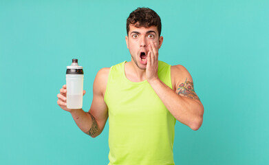fitness man feeling shocked and scared, looking terrified with open mouth and hands on cheeks