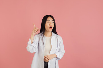 Asian young woman's portrait on pink studio background. Concept of human emotions, facial expression, youth, sales, ad.