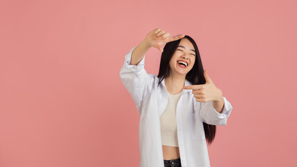 Asian young woman's portrait on pink studio background. Concept of human emotions, facial expression, youth, sales, ad.