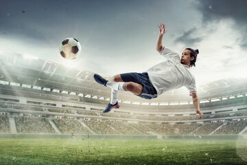 Male soccer, football player catching ball in jump at the stadium during sport match on dark sky background