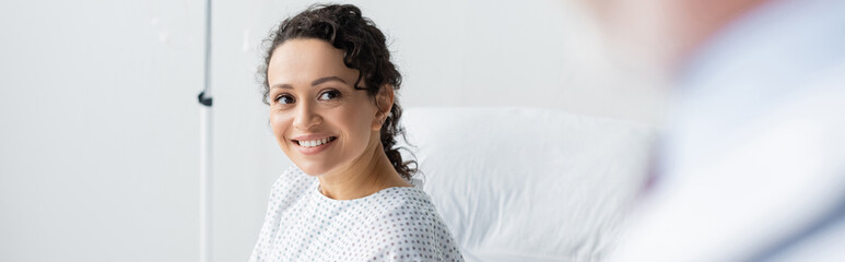 african american woman smiling near doctor on blurred foreground, banner