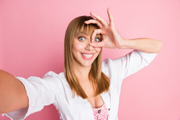 Photo portrait female blogger taking selfie showing okay gesture fingers near face smiling isolated on pastel pink color background