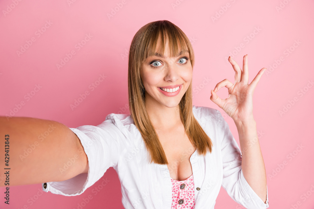 Canvas Prints Photo portrait female blogger taking selfie showing okay sign fingers smiling wearing white clothes isolated on pastel pink color background