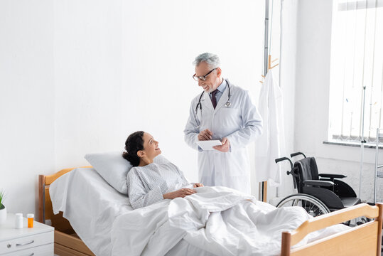 Smiling Doctor Holding Digital Tablet While Talking To African American Woman Near Wheelchair