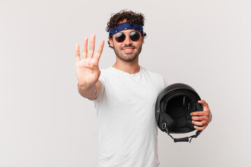 motorbike rider smiling and looking friendly, showing number four or fourth with hand forward,...