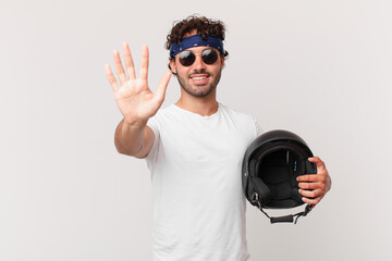 motorbike rider smiling and looking friendly, showing number five or fifth with hand forward,...