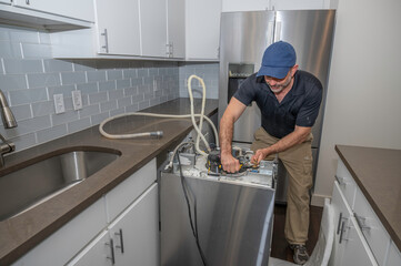 Appliance technician installing dishwasher hoses