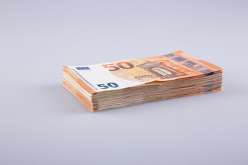 A stack of clear 50 euro banknotes on a gray background. 