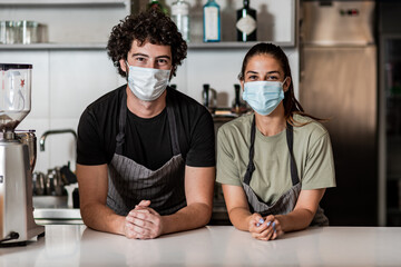 Team work spirit.Millennial business team wear protective masks, posing in coffee shop during corona virus.