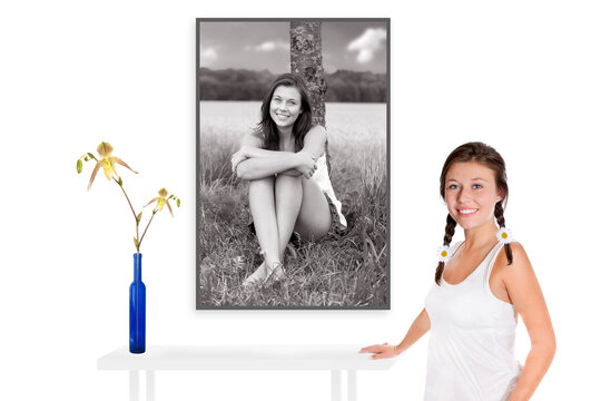 Beautiful young woman in front of a monochrome beauty portrait of herself, isolated on white background