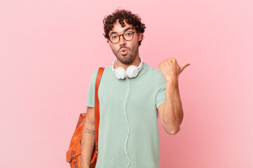 hispanic student looking astonished in disbelief, pointing at object on the side and saying wow,...