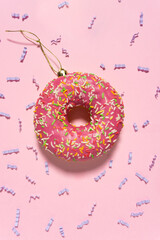 Creative concept photo of donut as christmas ball on pink background.