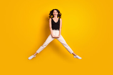 Fototapeta na wymiar Full length body size photo of woman jumping high in stylish outfit smiling happy isolated on bright yellow color background