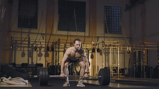Male athlete doing barbell snatch exercise. Slow motion