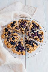 Freshly baked oat blueberry scones on cooling rack on white wooden background. Sweet food with natural ingredients. Vegan gluten free pastry..