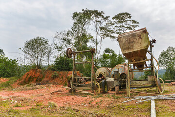 The rusty, decrepit concrete mixer was abandoned outdoors