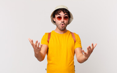 hispanic tourist man feeling extremely shocked and surprised, anxious and panicking, with a...