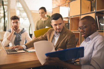 Colleagues working together in modern office using devices and gadgets during creative meeting