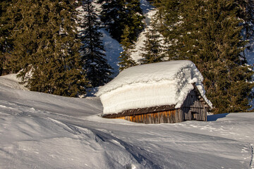 One mountain hut covered in layers of snow	