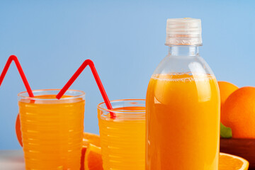 Bottle of orange juice and fresh oranges on table