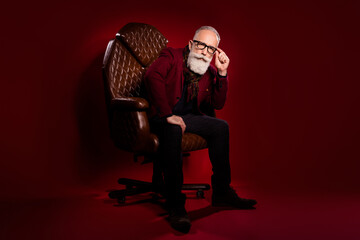 Full body photo of calm concentrated man sit in leather chair hand touch glasses isolated on dark...