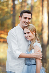 Fototapeta premium Happy young couple on a walk in the forest at sunset. The bride is wearing a blue wedding dress.