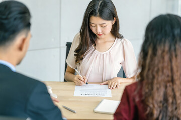 Young Asian woman signing the contract with two manager with positive motion in meeting room,Business Hiring new member , Job interview agreement, sign contract with manager concept