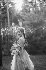 Happy bride in a blue dress laughs at sunset in the forest.