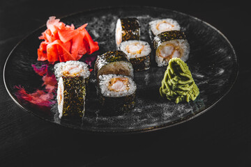 ushi roll with shrimp and rice in plate on black wooden table background