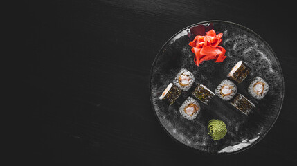 ushi roll with shrimp and rice in plate on black wooden table background
