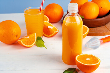 Bottle of orange juice and fresh oranges on table