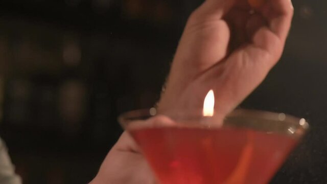 Bartender decorates a red cocktail with orange peel. cocktail in an elegant glass. Close up