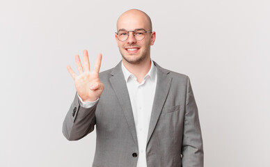 bald businessman smiling and looking friendly, showing number four or fourth with hand forward,...