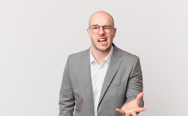 bald businessman looking angry, annoyed and frustrated screaming wtf or what’s wrong with you