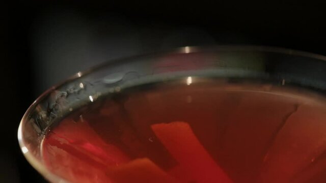 Bartender decorates a red cocktail with orange peel. cocktail in an elegant glass. Close up