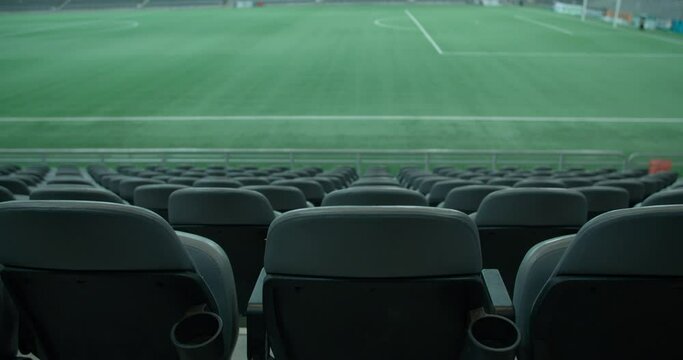 Empty seats of football stadium with green grass in background